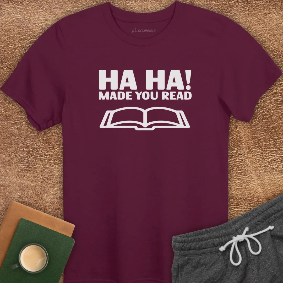 Maroon t-shirt with the text 'HA HA! MADE YOU READ' printed in white, accompanied by an image of an open book.