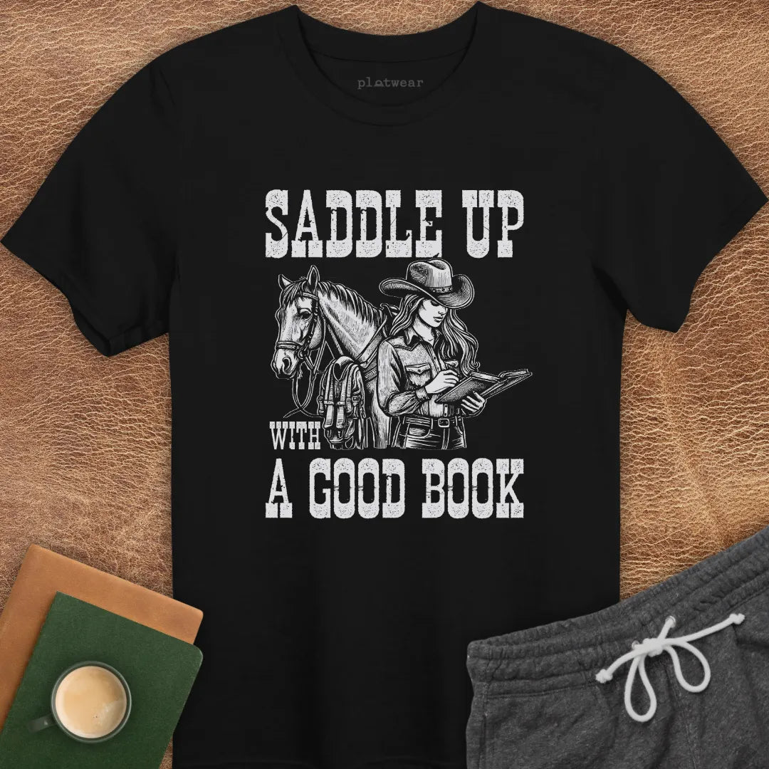A black crew neck t-shirt with a graphic print of a person on a horse and the phrase 'SADDLE UP WITH A GOOD BOOK'.