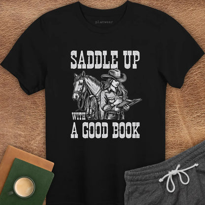 A black crew neck t-shirt with a graphic print of a person on a horse and the phrase 'SADDLE UP WITH A GOOD BOOK'.